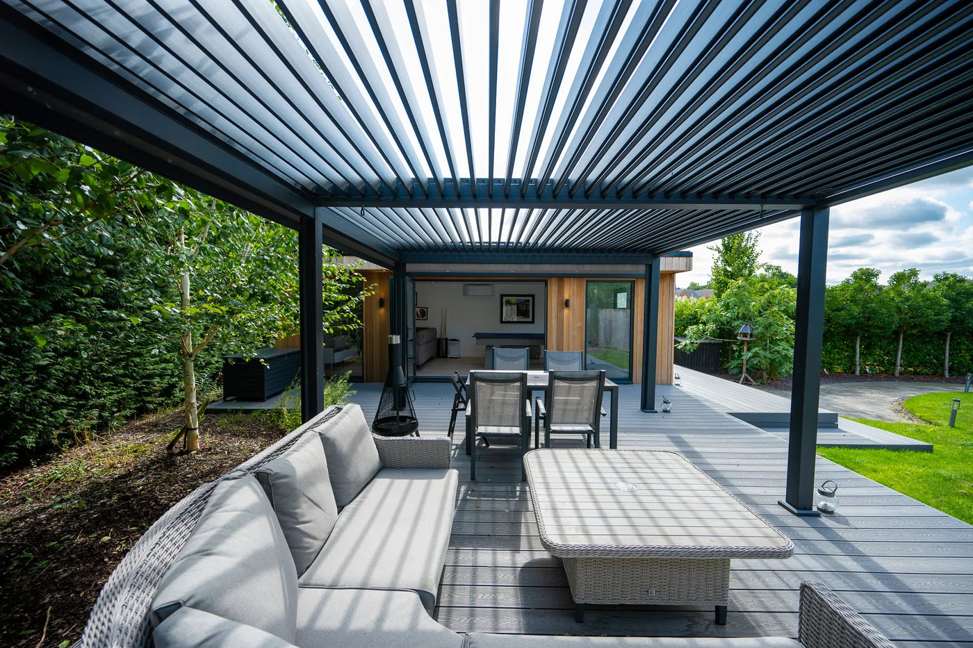Sunlight falling through open aluminium roof louvres onto garden seating