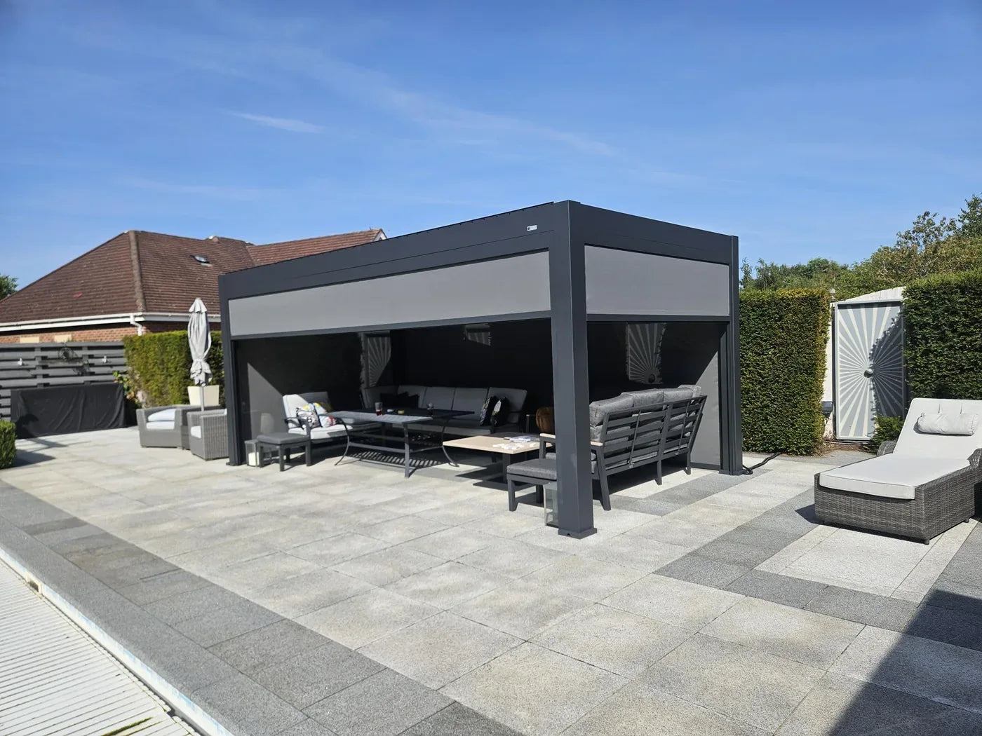 Tora pergola with lowered side screens and lounge seating on a paved customer patio