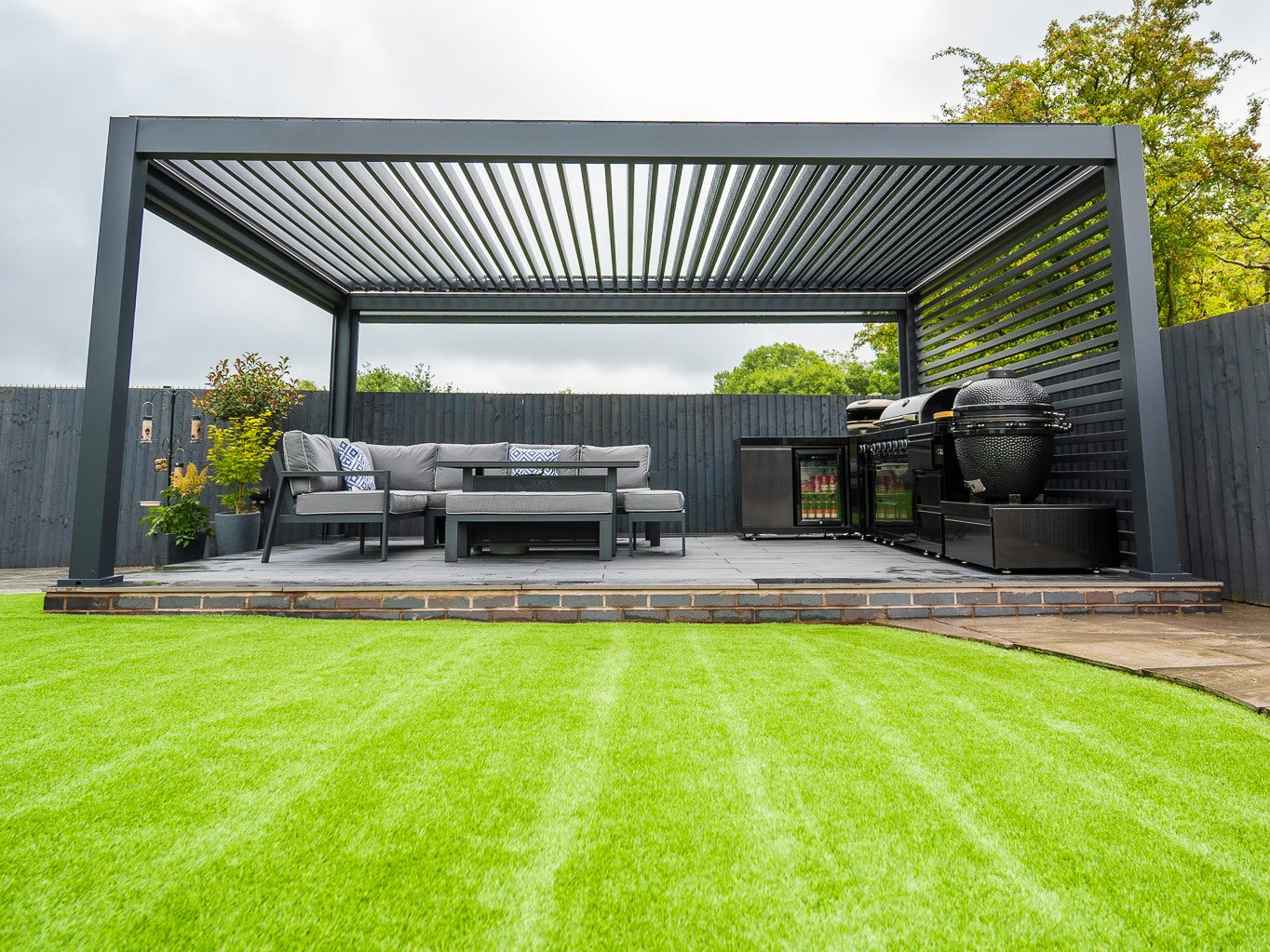 Real installation with a slatted side wall beside an outdoor kitchen and seating